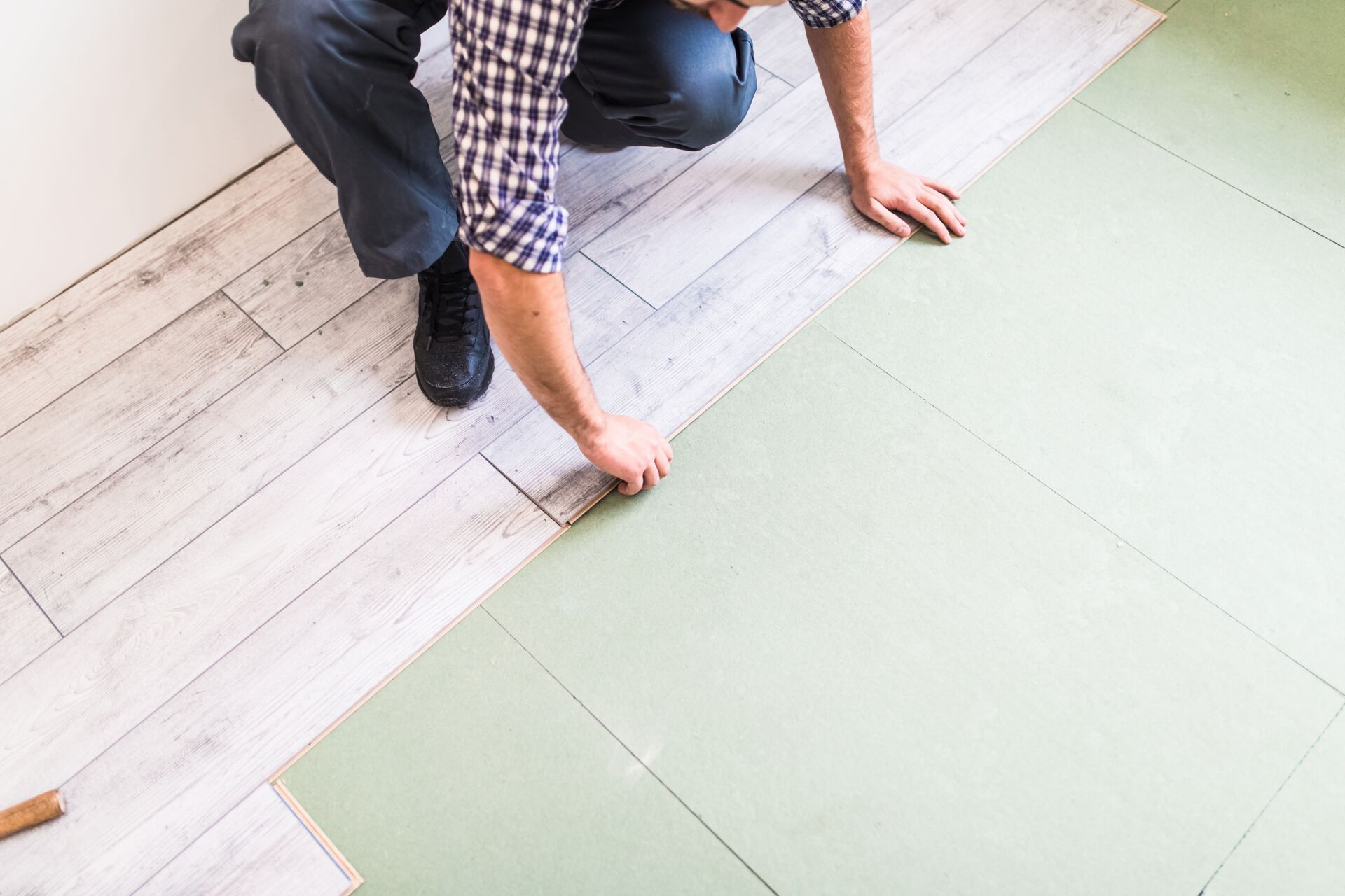 arbeiter-der-einen-boden-mit-hellen-laminatdielen-bearbeitet